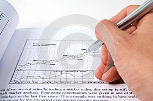 Hand with pen on stock chart