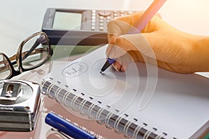 Hand with pen writing on notebook and working calculate