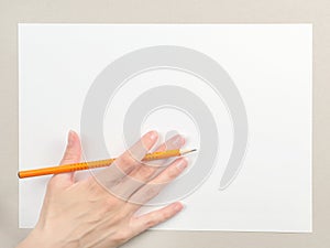 Hand with pencil on blank paper sheet