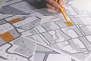 hand with pencil on cadastral map - choose and buy a building plot