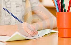 Hand with pencil writing in a notebook