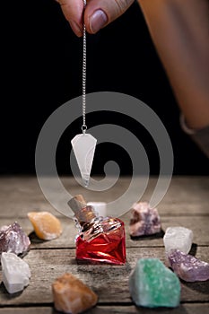 Hand with pendulum, an elixier and healing stones, fortuntelling and horoscope photo