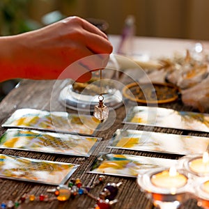 Hand with pendulum over tarot cards