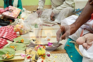 a hand performing hindu ritual pooja yajna indoor with flowers and brass utensil