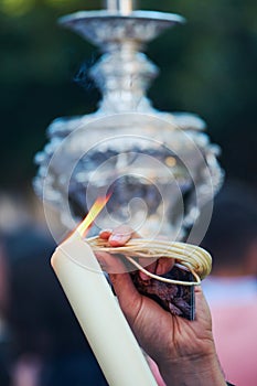 Hand of a person lighting a candle in a Holy Week procession