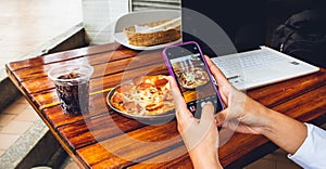 hand of person with mobile photographing food to publish on networks photo