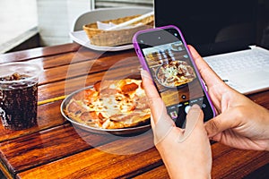 hand of person with mobile photographing food to publish on networks photo