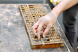 Hand of person playing and demonstration used of ancient Chinese abacus on old black wooden table