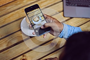 Hand, person and smartphone for coffee photography in table at cafe for art, project or social media post. Influencer