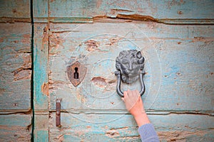 Hand of a person who knocks at a door knocker in the shape of medieval lion hoping to be accepted