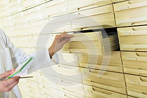 Hand of pharmaceutist opening drawer in farmacy photo