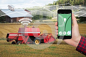 Hand with phone. On the screen control interface of the self driving combine harvester.