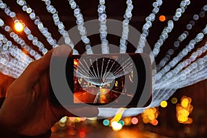 Hand with phone takes photos of lights, garlands