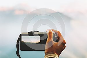 Hand with photo camera taking shot of mountains