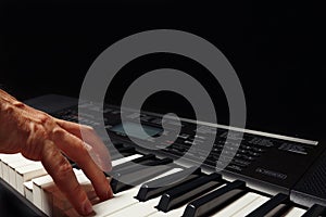 Hand of pianist playing the digital piano on black background