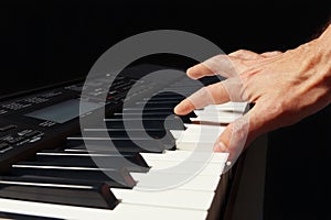 Hand of pianist playing the electronic piano on black background