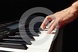 Hand of pianist playing the electronic synth on black background