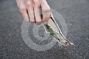 Hand pick one hundred dollar banknote from ground. Found money concept