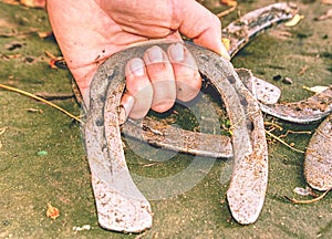 Hand pick up silver horseshoes from leaves  dotted ground