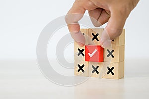 Hand picked check mark on cube wooden toy block stacked with cross symbol for true or false changing mindset or way of adapting to