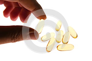 Hand picked Vitamin capsule gold colour isolated white background