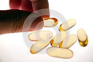 Hand picked Vitamin capsule gold colour isolated white background