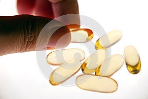 Hand picked Vitamin capsule gold colour isolated white background