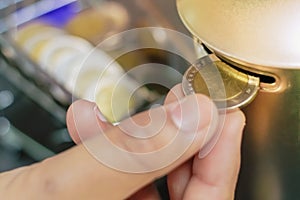 Hand picking coins into a coin bank wih mini Shopping cart background, Saving money concept.