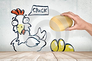 Hand picking egg from drawing chicken saying & x27;Cluck& x27; photo