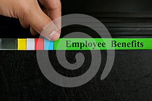 Hand picking employee benefits file in black binder folder. Human resources business concept.