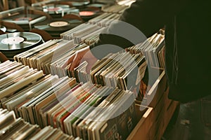 Hand picking old vinyl records from a shelf in a book store.