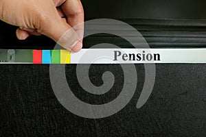 Hand picking pension file record in black binder folder. Pension benefit retirement concept.