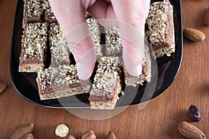 Hand picking piece of walnut cake from a plate