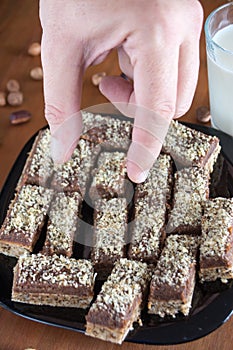 Hand picking piece of walnut cake from a plate