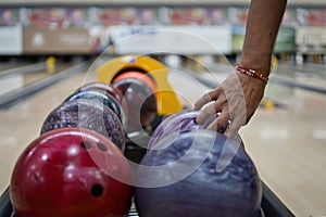 Hand picking up bowling ball in return machine at bowling alley.