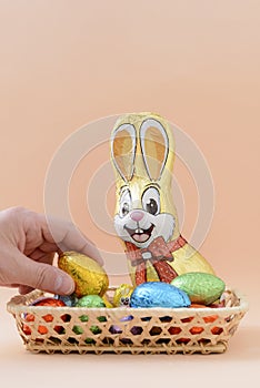 A hand picking up a chocolate Easter egg from a basket