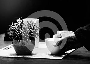 Hand picking up a cup of coffee on black background