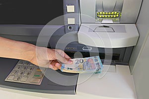 Hand picking up European â‚¬ 20 banknotes from the bank ATM