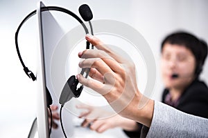 Hand picking up headphone that hanging on computer screen