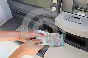 hand picking up money in European banknotes from an ATM bank cas