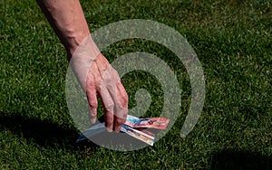 Hand picking up money from the ground. swiss currency. grass ground