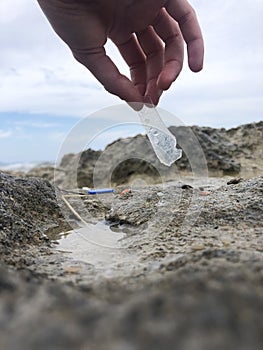Hand picking up a plastic from the beach