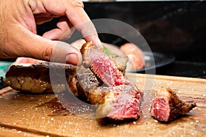 Hand picking up rare doneness picanha meat steak beef.