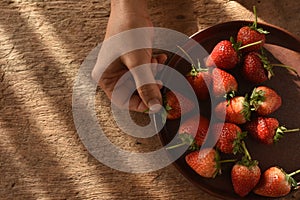 Hand picking up strawberry fruit.