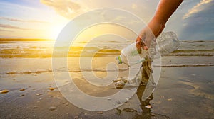 The hand is picking up trash on the beach, the idea of environmental conservation