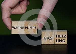 Hand picks cubes with the German text `Waermepumpe` heat pump instead of cubes with the text `Gas Heizung` gas heating. photo