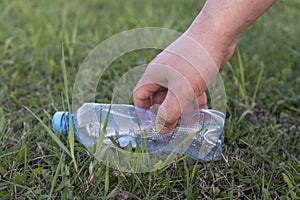 Hand picks up a plastic bottle from the grass