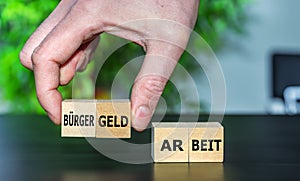 Hand picks wooden cubes with the German expression 'Buergergeld'.