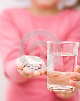 Hand with pills and glass of water