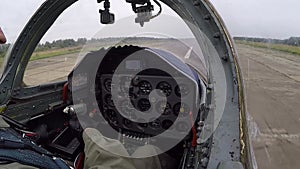Hand of pilot hold and control helm. Gray combat fighter plane land on runway of old empty aerodrome against a dark cloudy sky